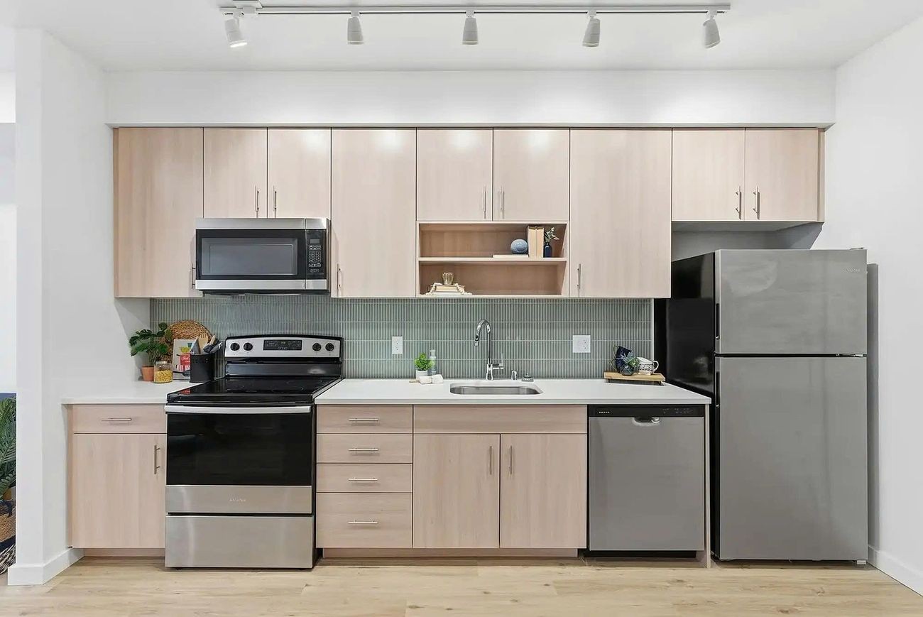 Model unit kitchen with casework, quartz counters, and plank flooring